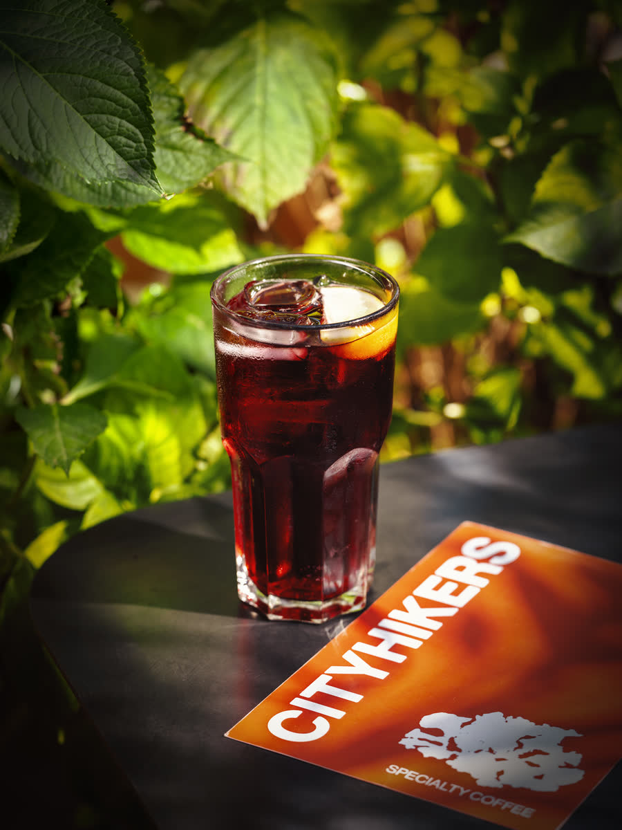 A tall glass of iced hibiscus tea with a slice of orange